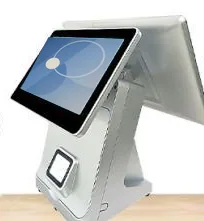 White dual-screen countertop terminal with a tilted customer touchscreen, rear operator display and scanner window, seen from the front quarter