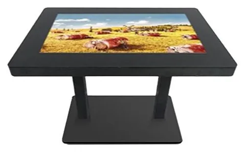 Black interactive touch table with a large landscape touchscreen set into a flat top, standing on twin pedestal legs